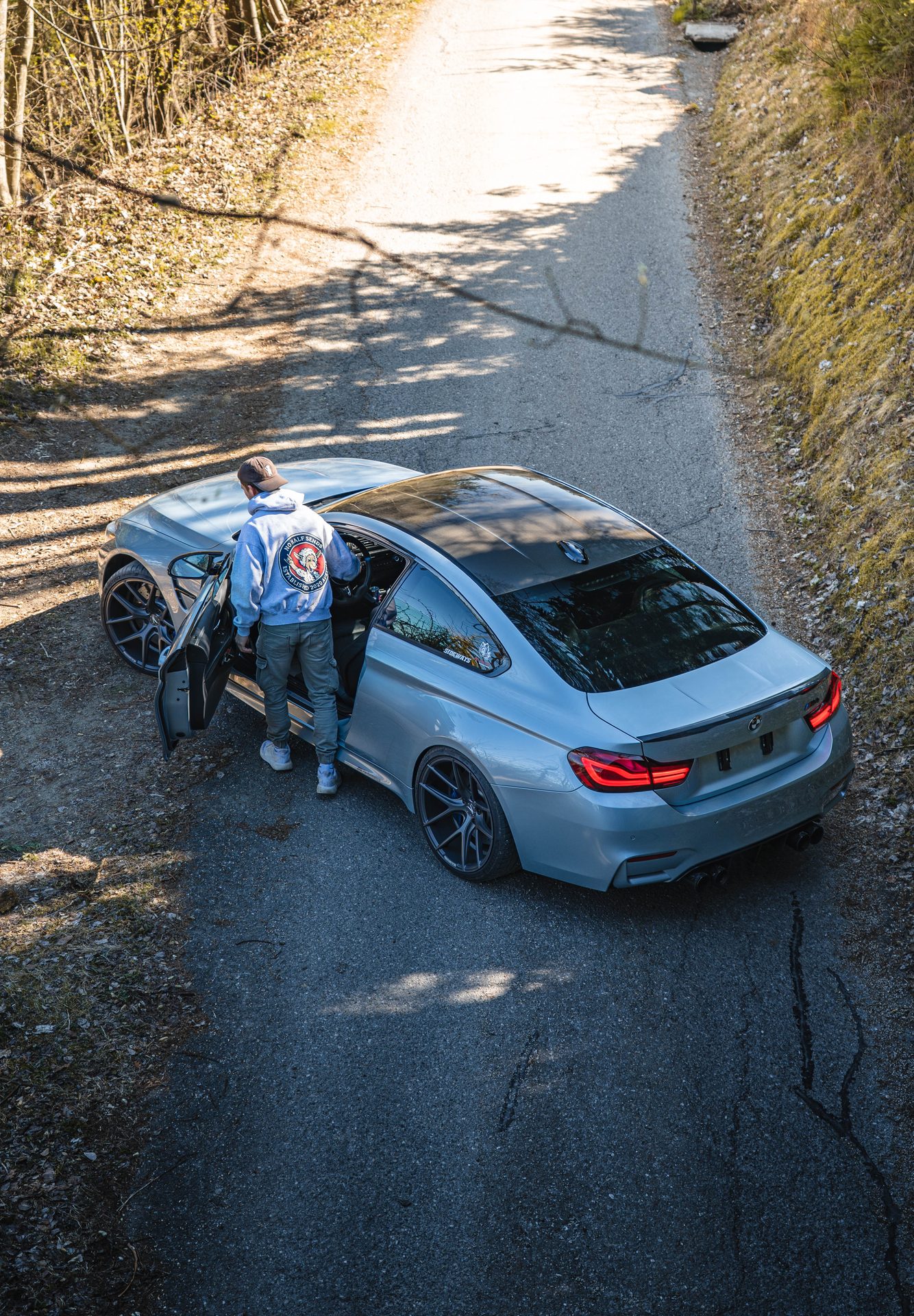 Autofotografie Kärnten — BMW M4 von oben mit geöffneter Fahrertür auf einer Bergstraße